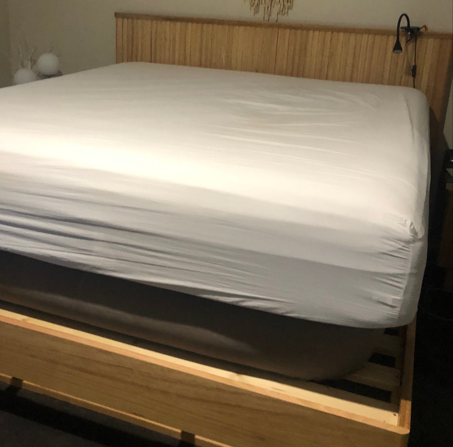 Mattress being held up by Bedezy with fresh white sheets on a wood slat base showing the height Bedezy can lift a king mattress.